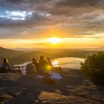 group of people sirring under sunset